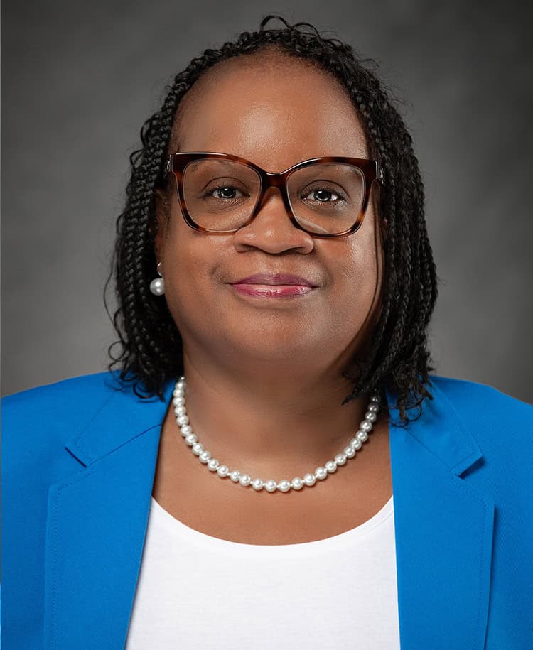 Nadine Edney at EPI Center, professional portrait of a confident woman in a blue blazer and glasses.